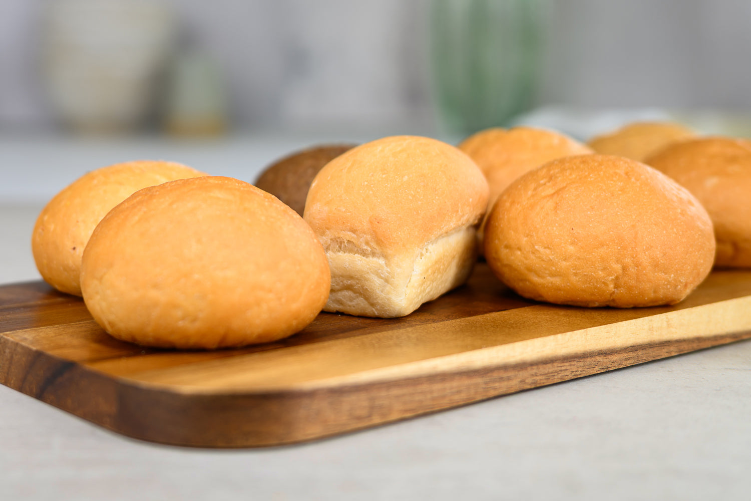 Wooden cutting board with freshly baked bread rolls on a neutral background. Dessert Kitchen About Breads