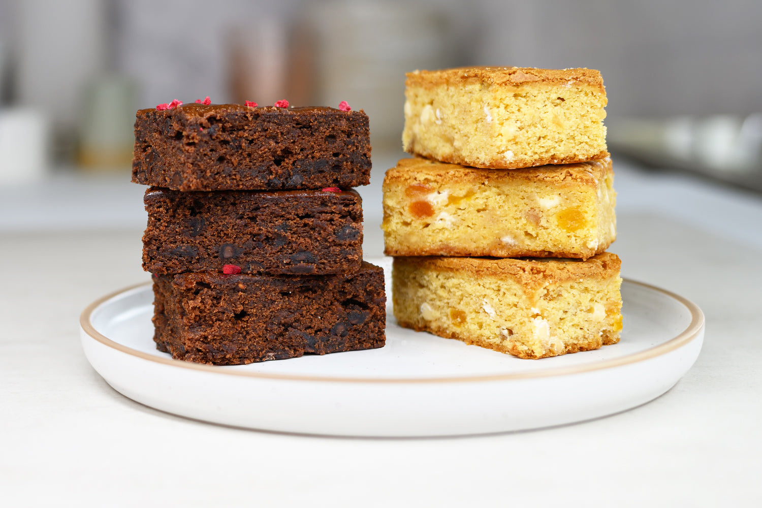 Stacks of brownies and blondies on a white plate with a blurred background. Dessert Kitchen Quality at Scale