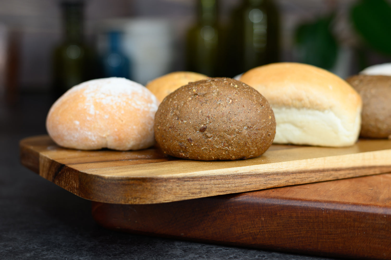 Assorted bread rolls on a wooden board with a blurred background. Dessert Kitchen Breads & Rolls