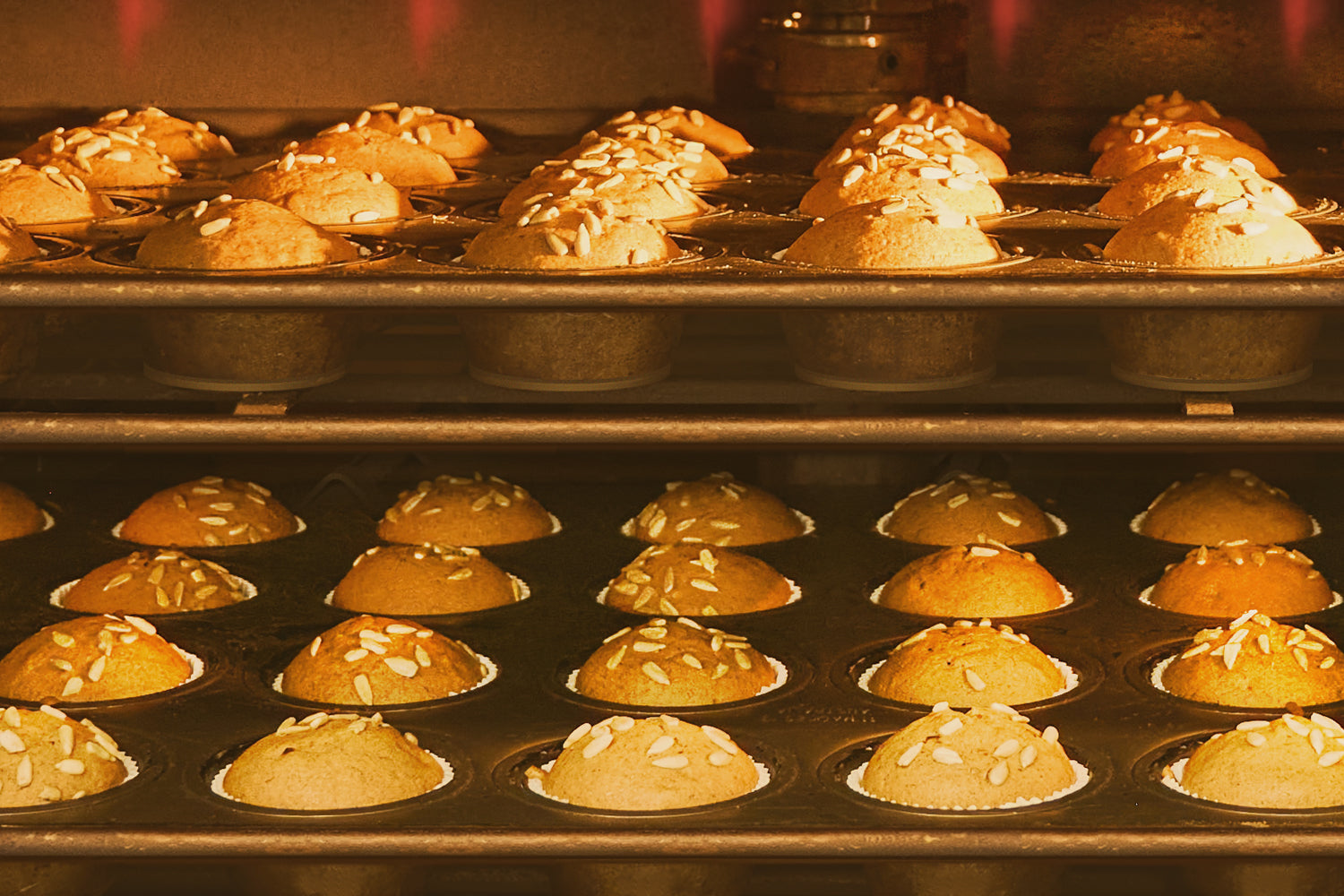 Baked goods in a muffin tin with a golden brown color, likely in an oven. Dessert Kitchen Quality at Scale