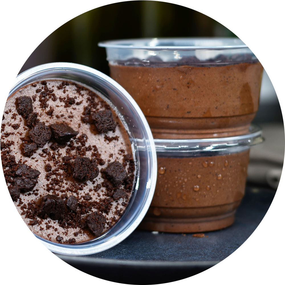 Two containers of chocolate dessert with cookie crumbles on a dark surface. Dessert Kitchen Partnerships