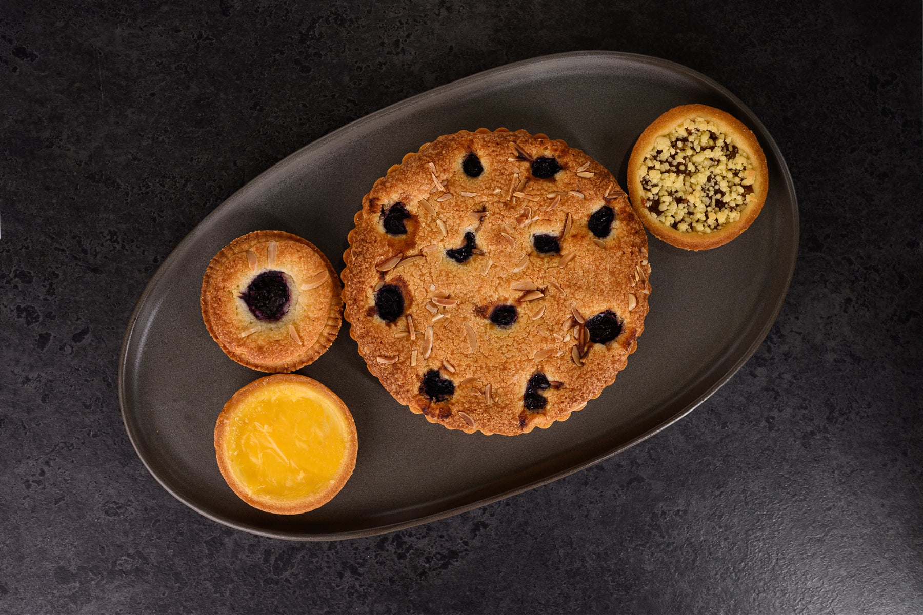 Assorted pies on a dark plate with a dark background. Dessert Kitchen