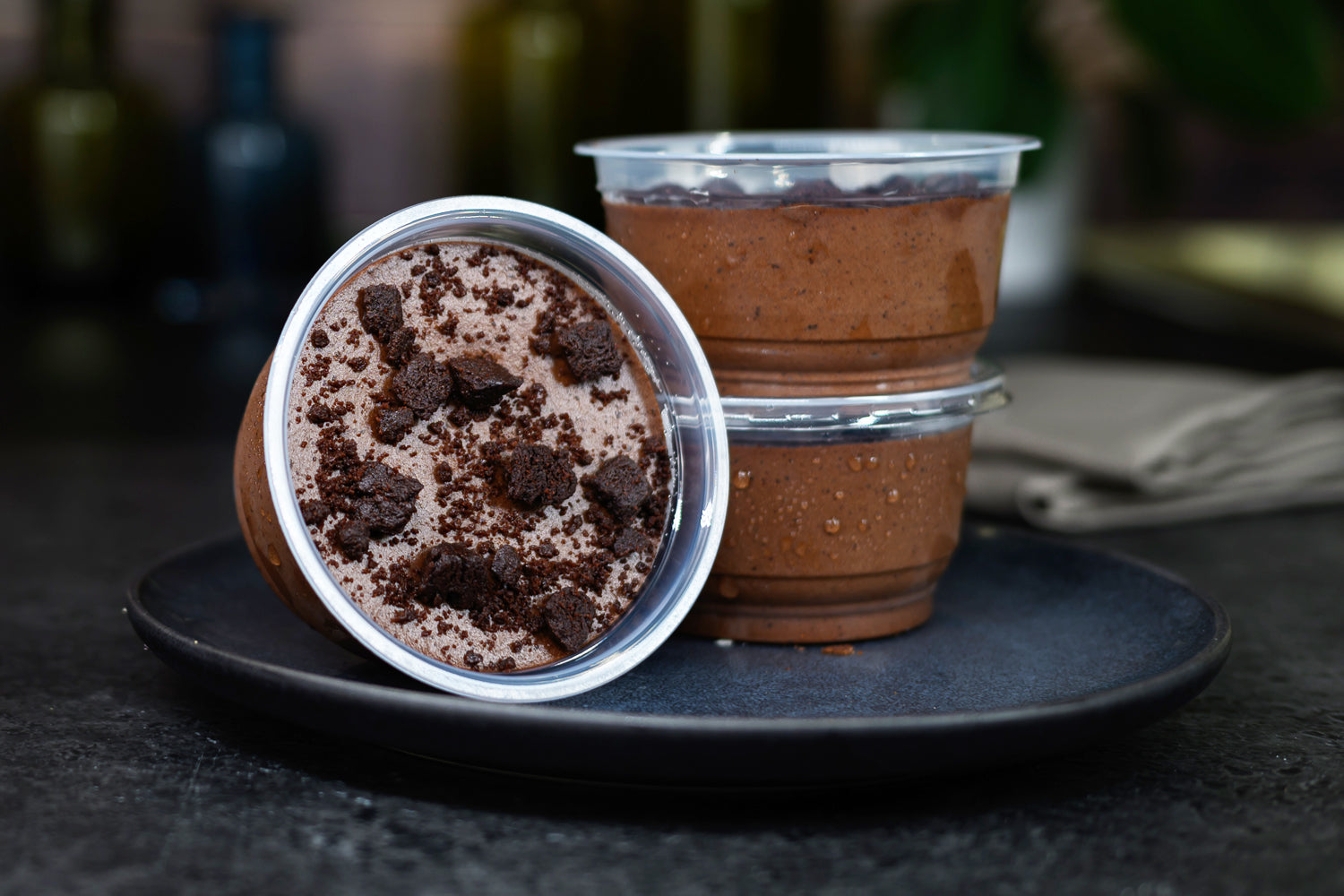 Two chocolate cups on a dark surface with a blurred background. Dessert Kitchen Mousses & Desserts