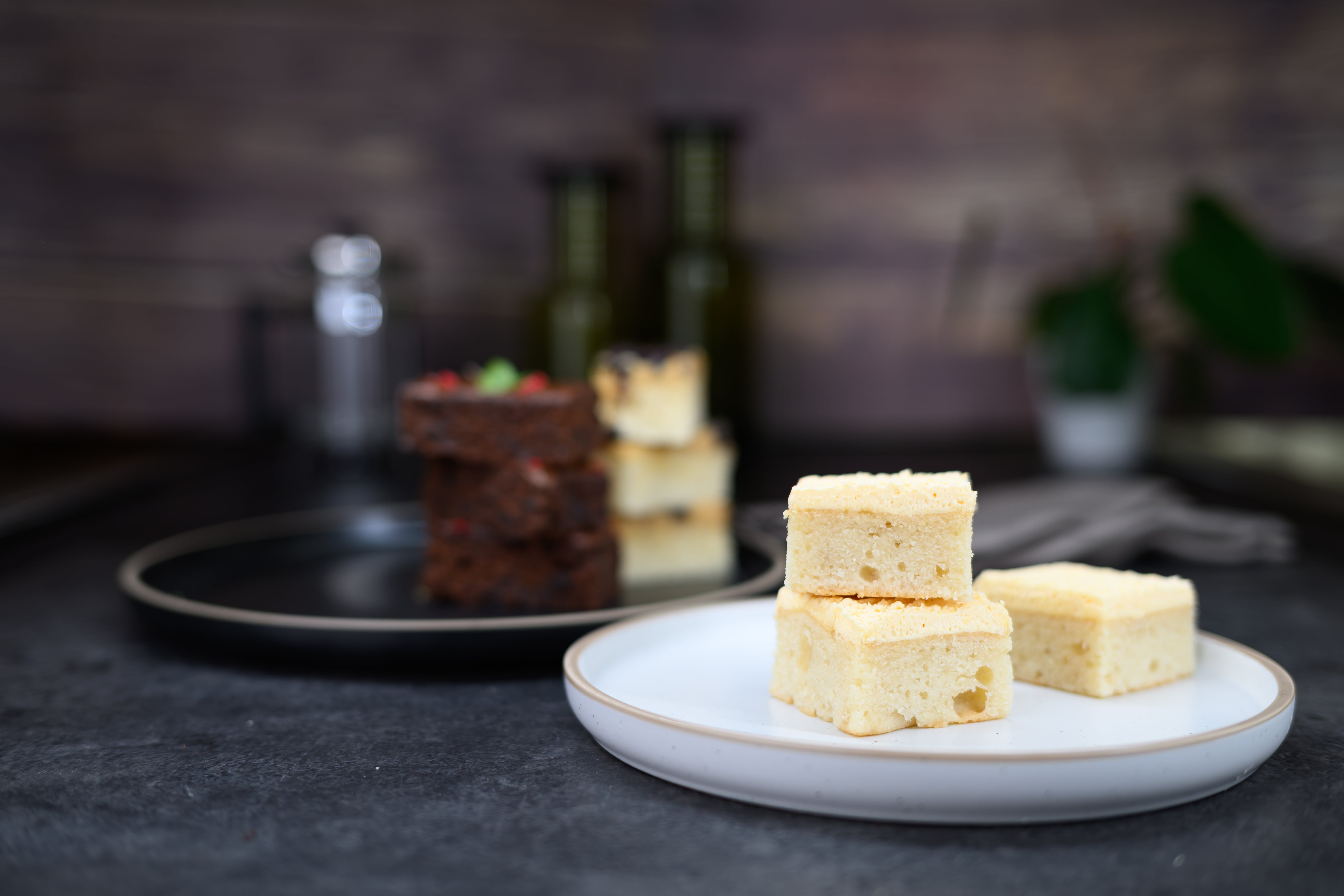Three pieces of cake on a white plate with a blurred kitchen background. Dessert Kitchen Cake Examples