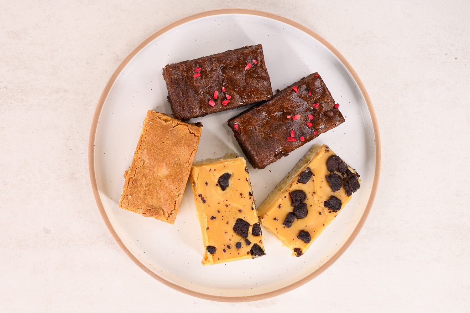 Assorted brownies on a white plate with a beige background. Dessert Kitchen Desserts