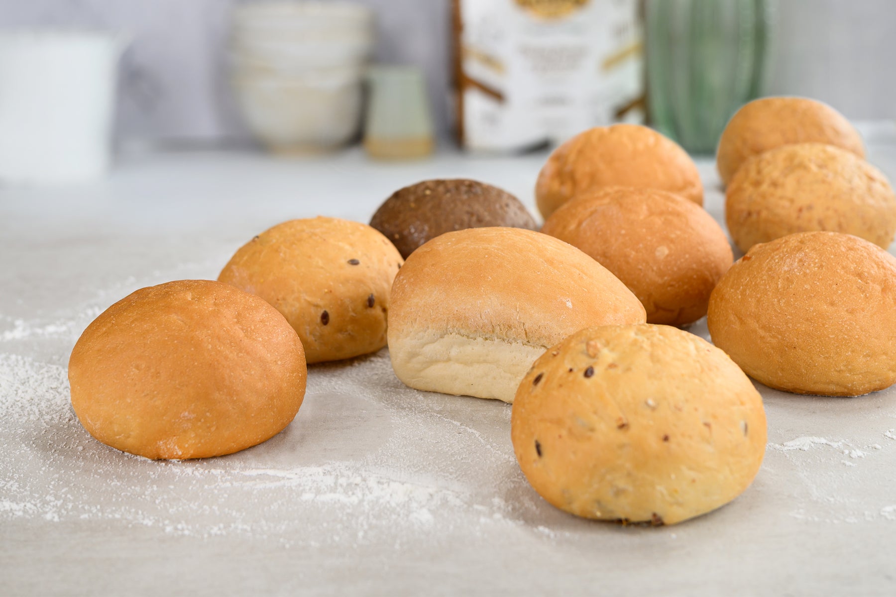 Assorted bread rolls on a floured surface with a blurred background. Dessert Kitchen Breads & Rolls