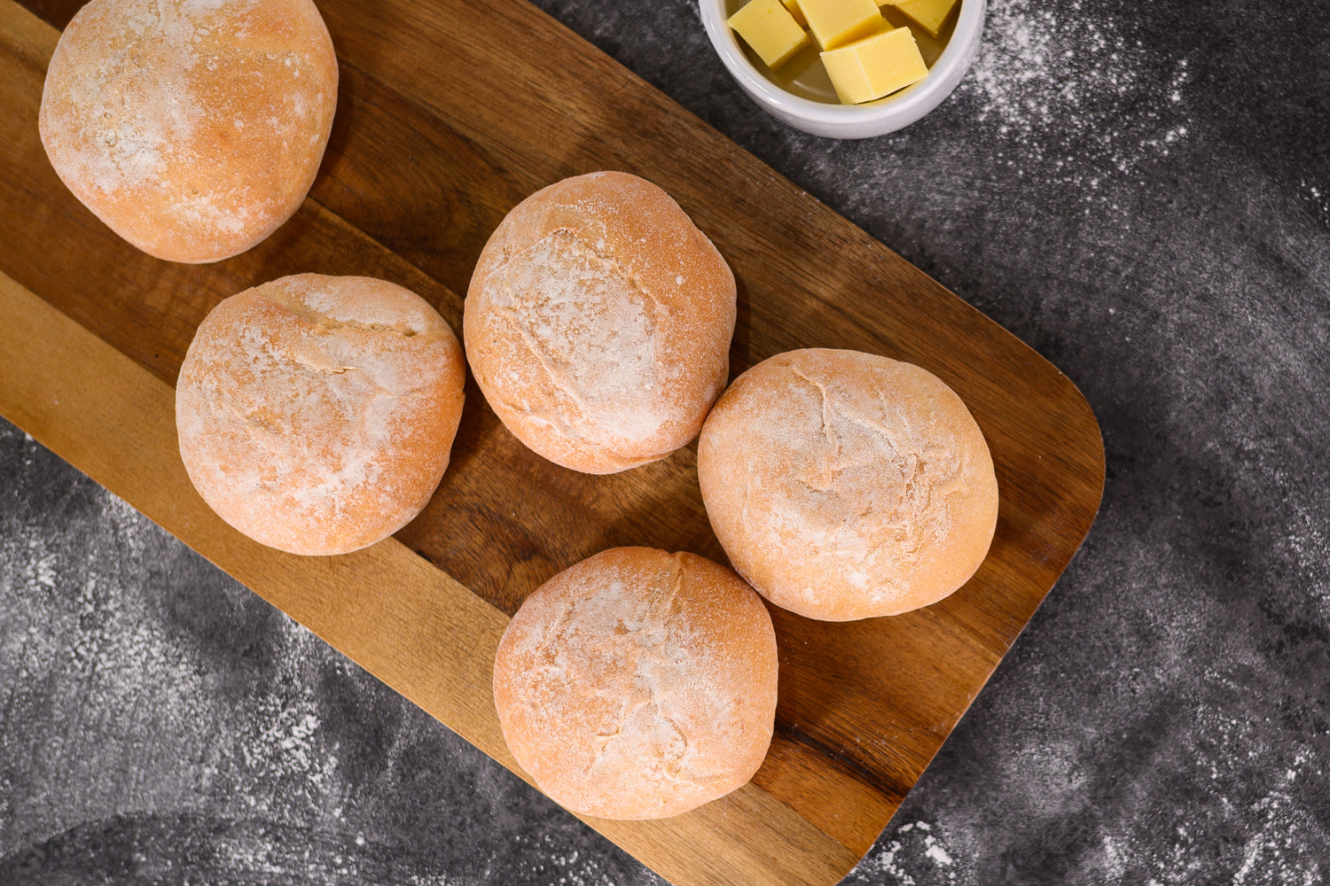 Wooden board with six bread rolls on a dark surface. Dessert Kitchen Breads & Rolls