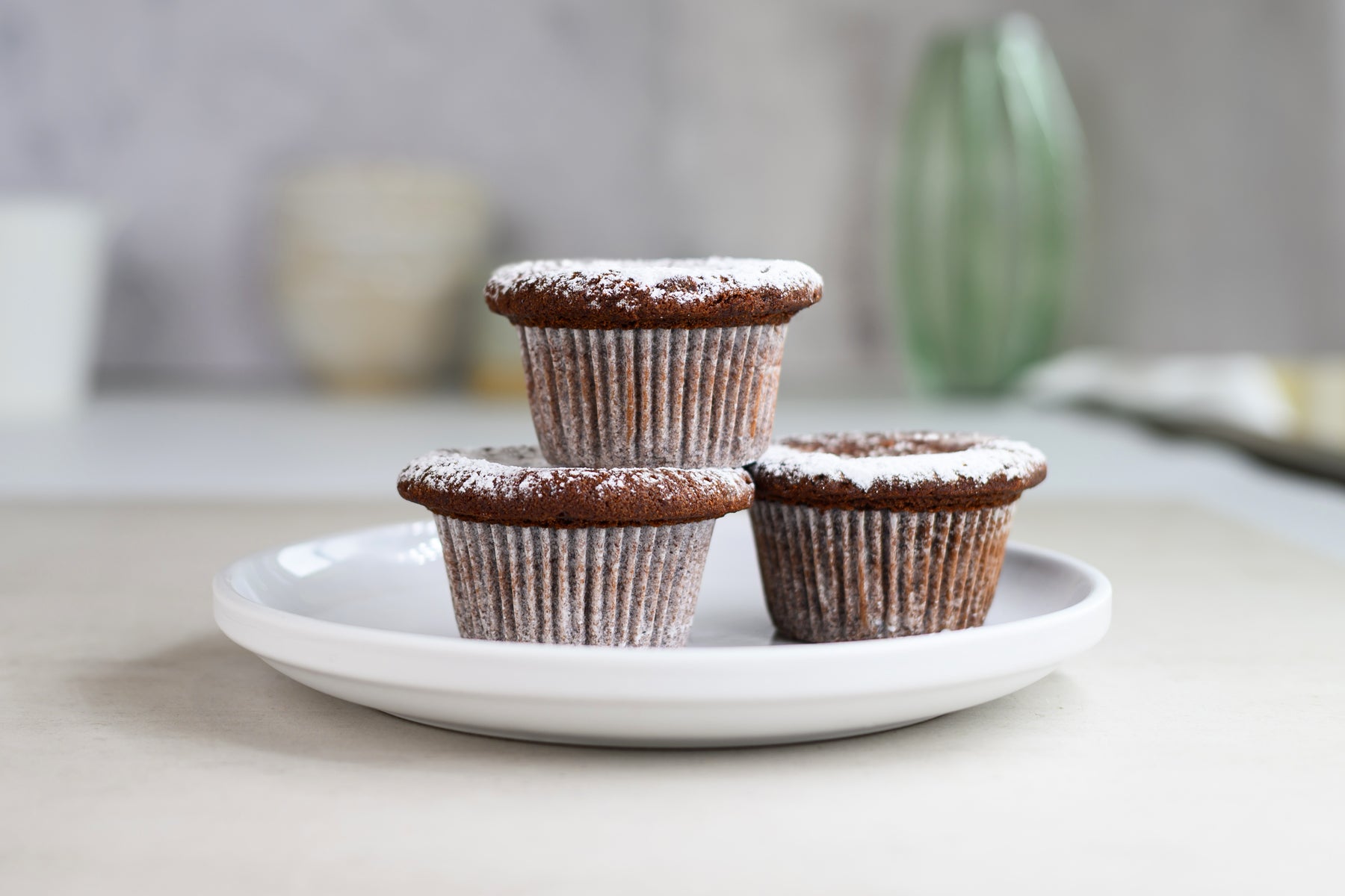Three chocolate cupcakes on a white plate with a blurred background. Dessert Kitchen Desserts