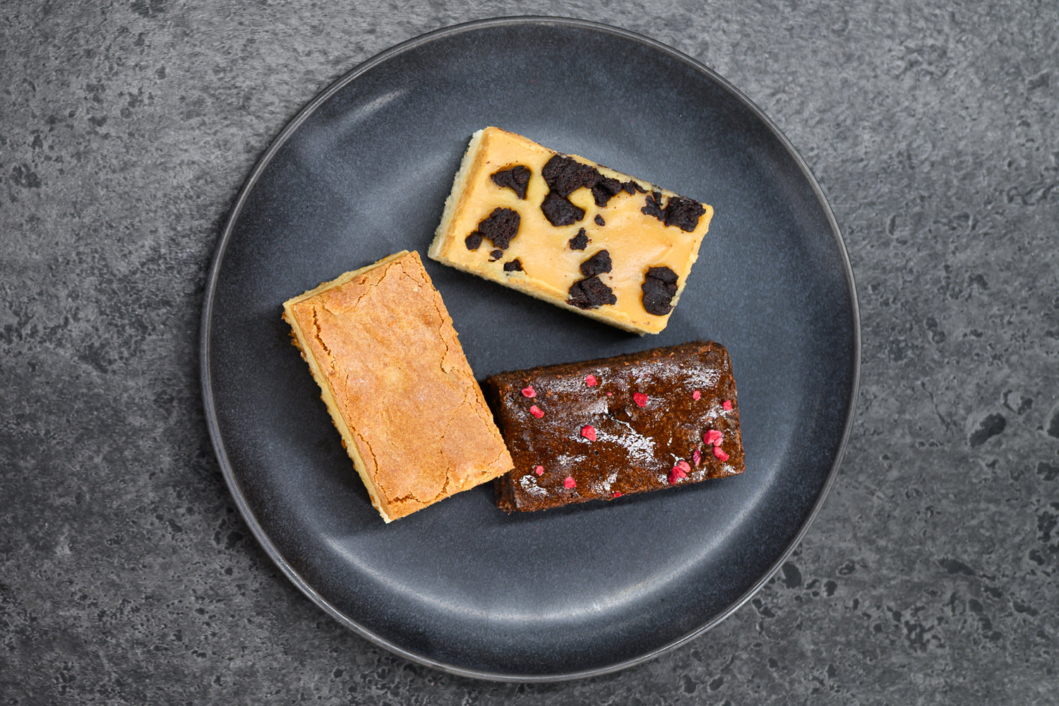 Three different types of desserts on a dark plate with a dark background. Dessert Kitchen Desserts