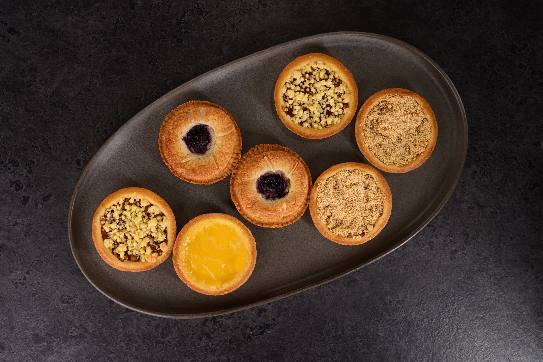 Assorted pastries on a dark plate against a dark background. Dessert Kitchen Desserts