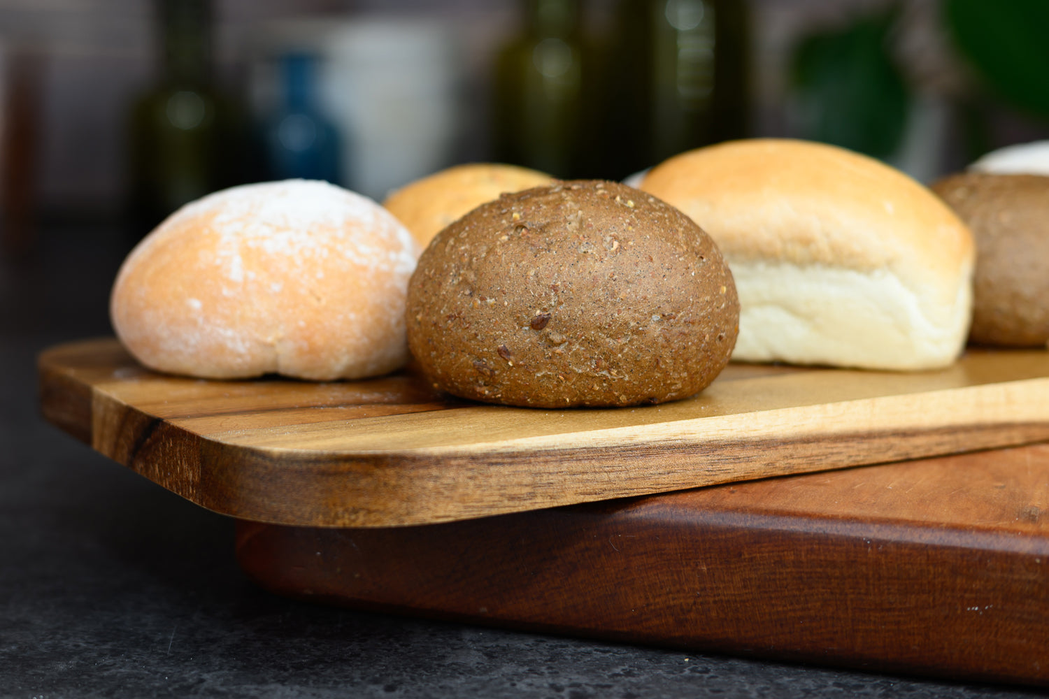 Three bread rolls on a wooden cutting board with a blurred background. Dessert Kitchen Breads & Rolls